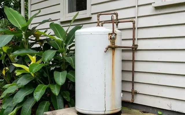 An ageing electric storage cylinder against a weatherboard wall